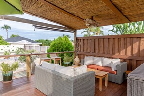 Une terrasse extérieure aménagée avec des meubles en osier, une table en bois et un toit de chaume.