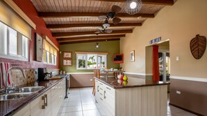 Una cuina amb una illa central, bigues de sostre de fusta i vista cap a l'exterior.