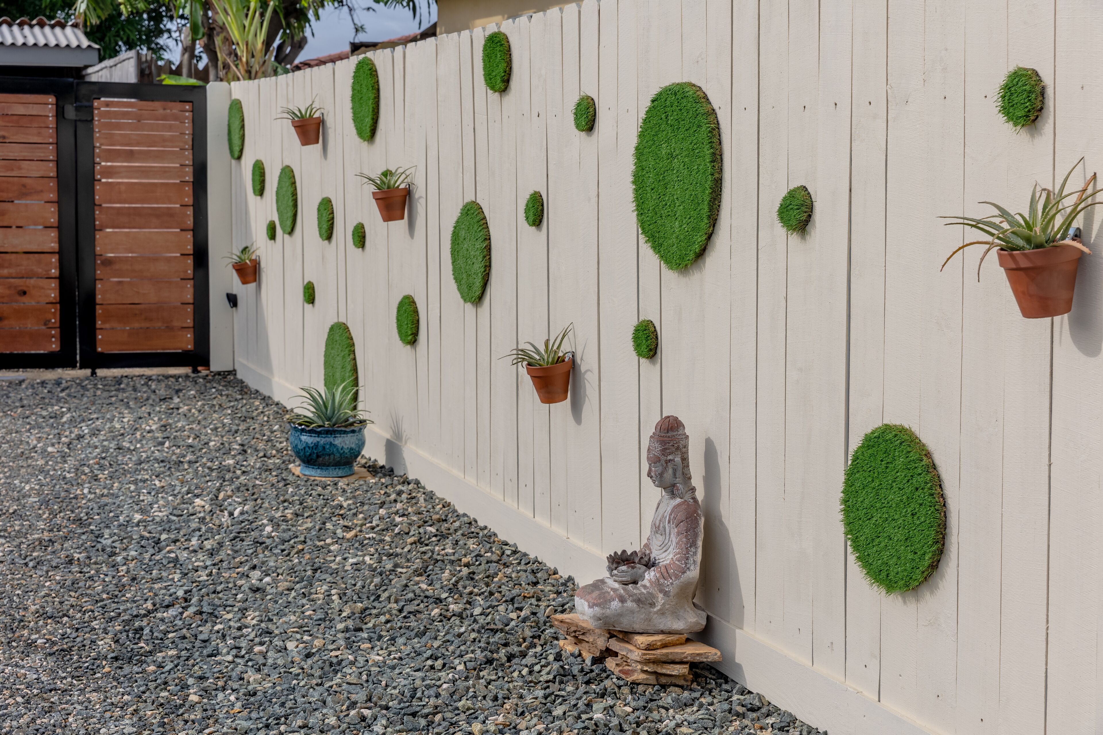 A wall with various potted plants and a statue.