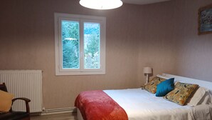 Une chambre à coucher avec un lit, une fenêtre, un radiateur, une chaise et une lampe.