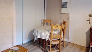 Un petit coin repas avec une table et des chaises, un plancher en bois et une porte blanche.