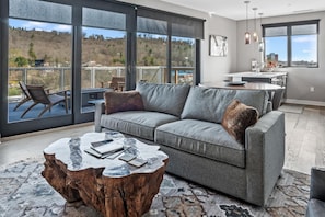 Relax in this stylish living room with a sofa, coffee table, and dining area offering a view of the surrounding hills.