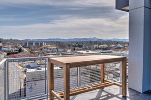 Enjoy a city view from this balcony with a table and clear views of the surrounding mountains.