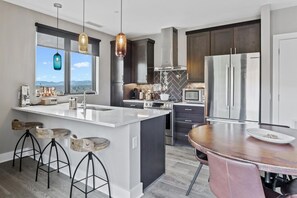 Enjoy cooking in this well-lit kitchen with a large island and bar stools, featuring a refrigerator and microwave.