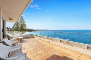 Relax on the spacious balcony with ocean views, a comfortable seating area, and a glass railing for a safe and unobstructed view.