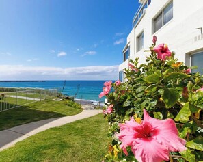 Enjoy breathtaking ocean views from this residence's balcony, surrounded by a well-manicured lawn and a pathway to the sea.