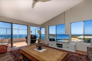 Relax in this spacious living room with expansive ocean views, a central coffee table, and comfortable seating.
