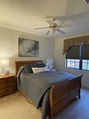 A bedroom with a bed, a nightstand, a ceiling fan, a window with curtains, and a wall-mounted artwork. -  Resort home, walk to it all, swim in two lush resort pools. (Naples)