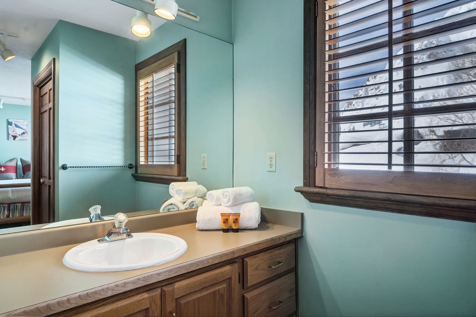 Une salle de bain avec un lavabo, un miroir, des meubles en bois et des serviettes.