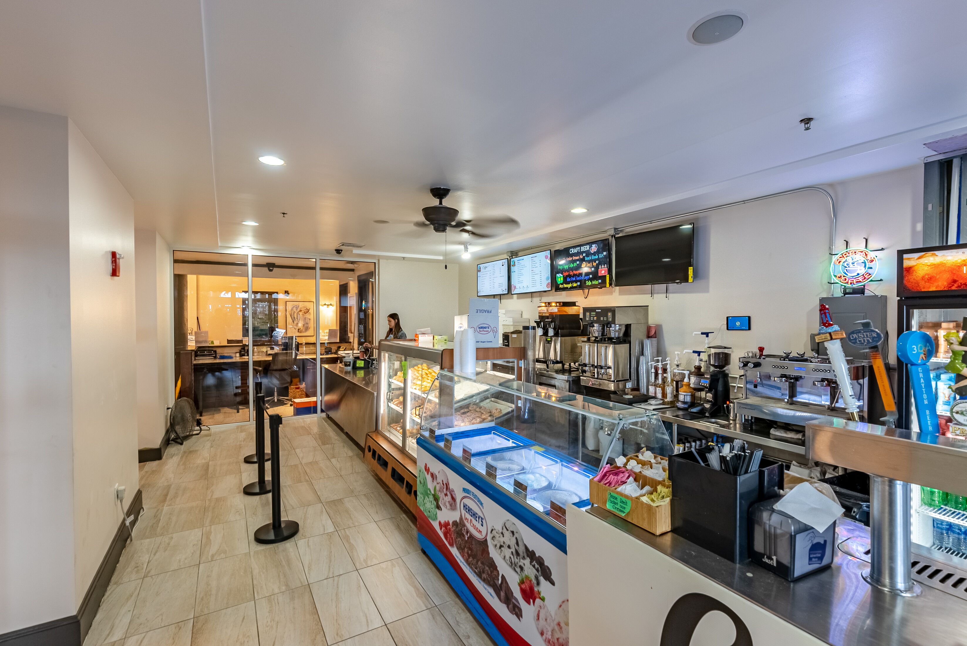 Un café moderno con un mostrador de autoservicio para helados, una máquina de café y una pizarra con el menú.