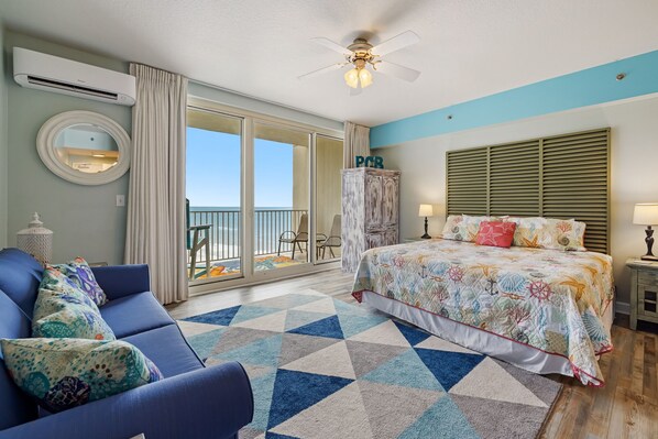 Une chambre avec un lit, un canapé bleu, un tapis à motifs et un balcon avec vue.