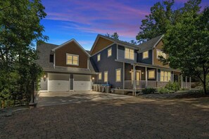Een tweelaags huis met garage, overdekte veranda en een oprit van baksteen.
