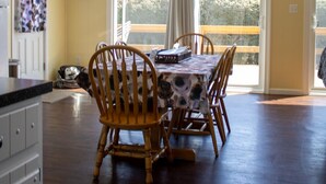 A dining area with a table and chairs, a kitchen with cabinets, and a large window with a view of greenery. - Dog Lover's Chalet w/ Fenced Yard, AMAZING VIEW 10mi to Camelback/Hiking/Casino (Sciota)