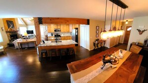Amplia sala de estar con un gran comedor de madera, una cocina con armarios de madera y una chimenea.