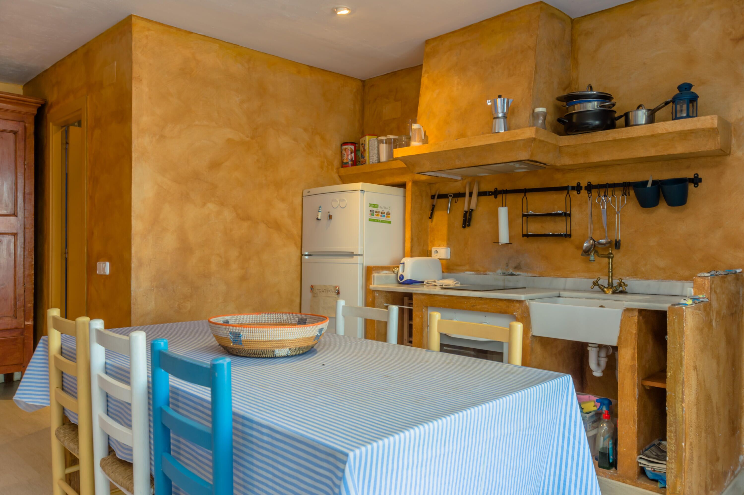 A compact kitchen with a table, chairs, and a refrigerator.
