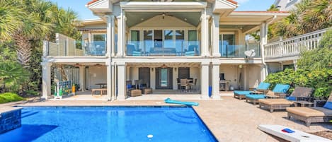 A two-story house with a swimming pool, outdoor furniture, and a covered patio area.