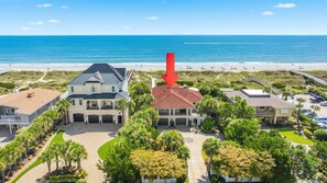 A beachfront property with a large house, a smaller house, and a parking area.