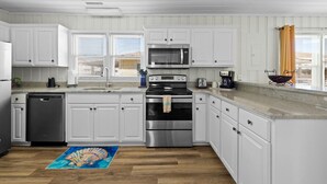 A modern kitchen with white cabinetry, stainless steel appliances, and a wooden floor.
