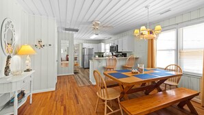 A spacious kitchen with wooden flooring, white cabinetry, and a dining area with a wooden table and chairs.