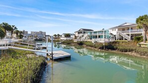 A waterfront property with a dock, a small boat, and a building with a balcony overlooking the water.