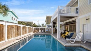 A swimming pool with a wooden fence, lounge chairs, and a covered area with tables and chairs. - Enjoy a Luxury Rental at Salt Life - Private Pool & Ocean View Balcony (North Myrtle Beach)