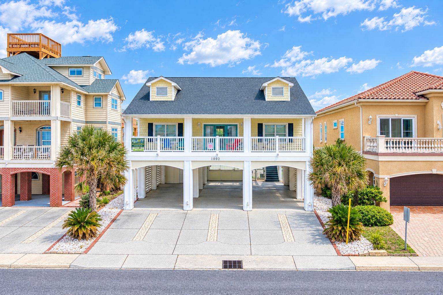 A multi-story residential building with a central entrance, balconies, and a parking area.