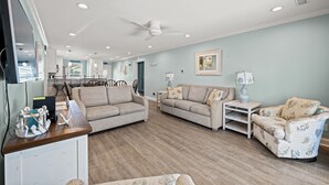 A spacious living room with a wooden floor, two beige sofas, a patterned armchair, and a small side table. - Enjoy a Luxury Rental at Salt Life - Private Pool & Ocean View Balcony (North Myrtle Beach)