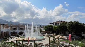 A courtyard with a central fountain, lounge chairs, and a building with a sign reading "HAMAM".