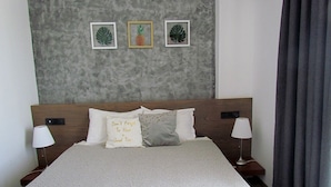 Una cama bien hecha con una colcha estampada, dos almohadas y dos toallas enrolladas.