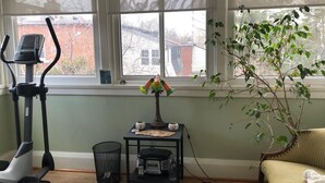 Een kamer met een hometrainer, een tafeltje met decoratieve objecten, een plant en een bank.