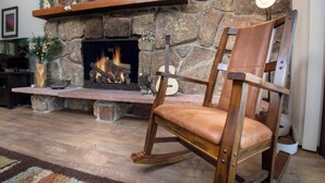Una sala de estar acogedora con chimenea de piedra, una mecedora de madera y un televisor.