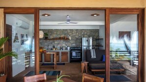 A modern kitchen with a stone backsplash, wooden cabinets, and a built-in oven. - Lazuli Playa - Beachfront Loft (Santa Maria Tonameca)
