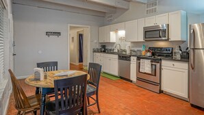 A kitchen with white cabinets, a stainless steel refrigerator, a microwave, and an oven. There is a dining table with chairs and a "Welcome" sign on the wall. - #2 in Old Town, 2bd/2ba, near I-40 (Albuquerque)