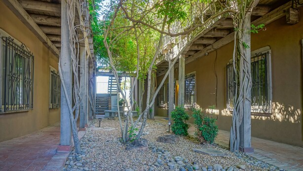 A covered walkway with stone flooring, trees, and a small garden area. - #2 in Old Town, 2bd/2ba, near I-40 (Albuquerque)