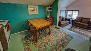 A cozy living room with a wooden dining table, a sofa, and a patterned rug. - Upper Level Loft in Downtown Suttons Bay Across the Street From Beach and Marina (Suttons Bay)