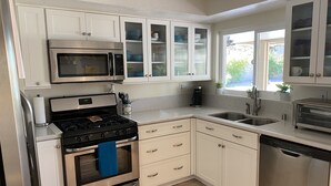 A modern kitchen with white cabinets, stainless steel appliances, and a window providing natural light. - Retreat w/ Pool  & Spa Home in Palm Desert 
There is a 300.00 fee to heat pool 
 (Palm Desert)