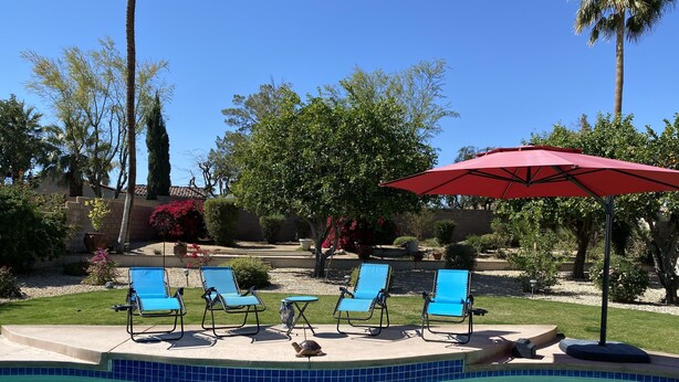 A swimming pool with blue chairs and a red umbrella. - Retreat w/ Pool  & Spa Home in Palm Desert 
There is a 300.00 fee to heat pool 
 (Palm Desert)