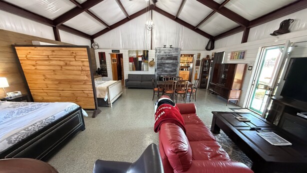 Een ruime woonkamer met een rode bank, een houten bed en een eethoek.