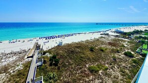 A beach with umbrellas, a pier, and a boardwalk. - Destin West Gulfside #309 ~Free Beach Service! Great View! Pools + Lazy River! (Fort Walton Beach)
