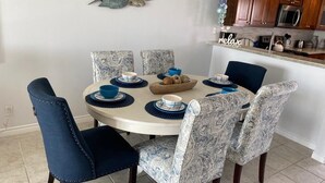 Ein Essbereich mit einem runden Tisch, blau-weißen Stühlen mit Muster und einer dekorativen Wandgestaltung.
