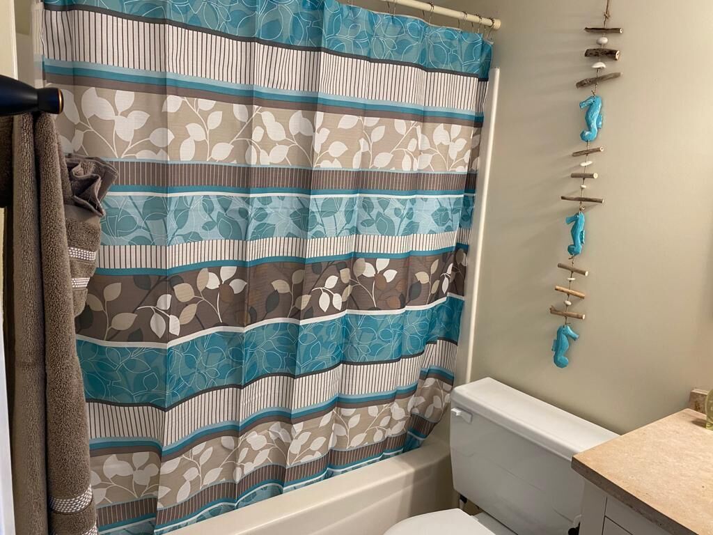 Ein Badezimmer mit gestreiftem Duschvorhang, Toilette und einem Wandregal mit Handtüchern.
