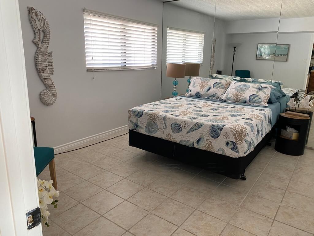 A bedroom with a bed, two windows, a wall decoration, and a lamp.