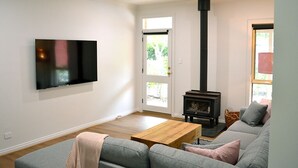 A modern living room with a grey sofa, a wooden coffee table, a black fireplace, and a flat-screen TV mounted on the wall. - The Blush 1 - Style in the vines (Penwortham)