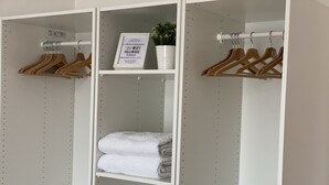 A white closet with wooden hangers, a folded white towel, and a sign with text. - Appartamento Stazione Termini A/C WI FI (Roma)