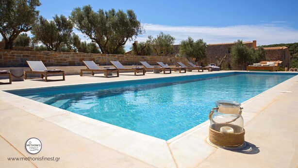 Una piscina con sillones de descanso y un tarro de vidrio en el borde.