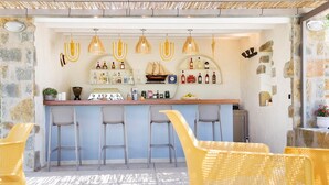 Zona de bar con pared de piedra, luces colgantes y taburetes.