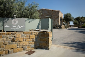 Un mur de pierre sur lequel est apposée une enseigne indiquant « Afentiko Pigadi, villas de luxe ».