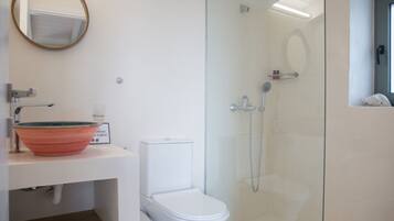 A bathroom with a glass-enclosed shower, a white toilet, and a sink with a decorative bowl.