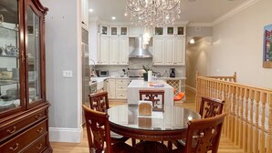 A dining area with a round table, wooden chairs, a chandelier, and white cabinetry.