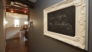 Un tableau noir sur lequel est écrit « La vigne des Cailliez », le tout encadré dans un cadre décoratif.